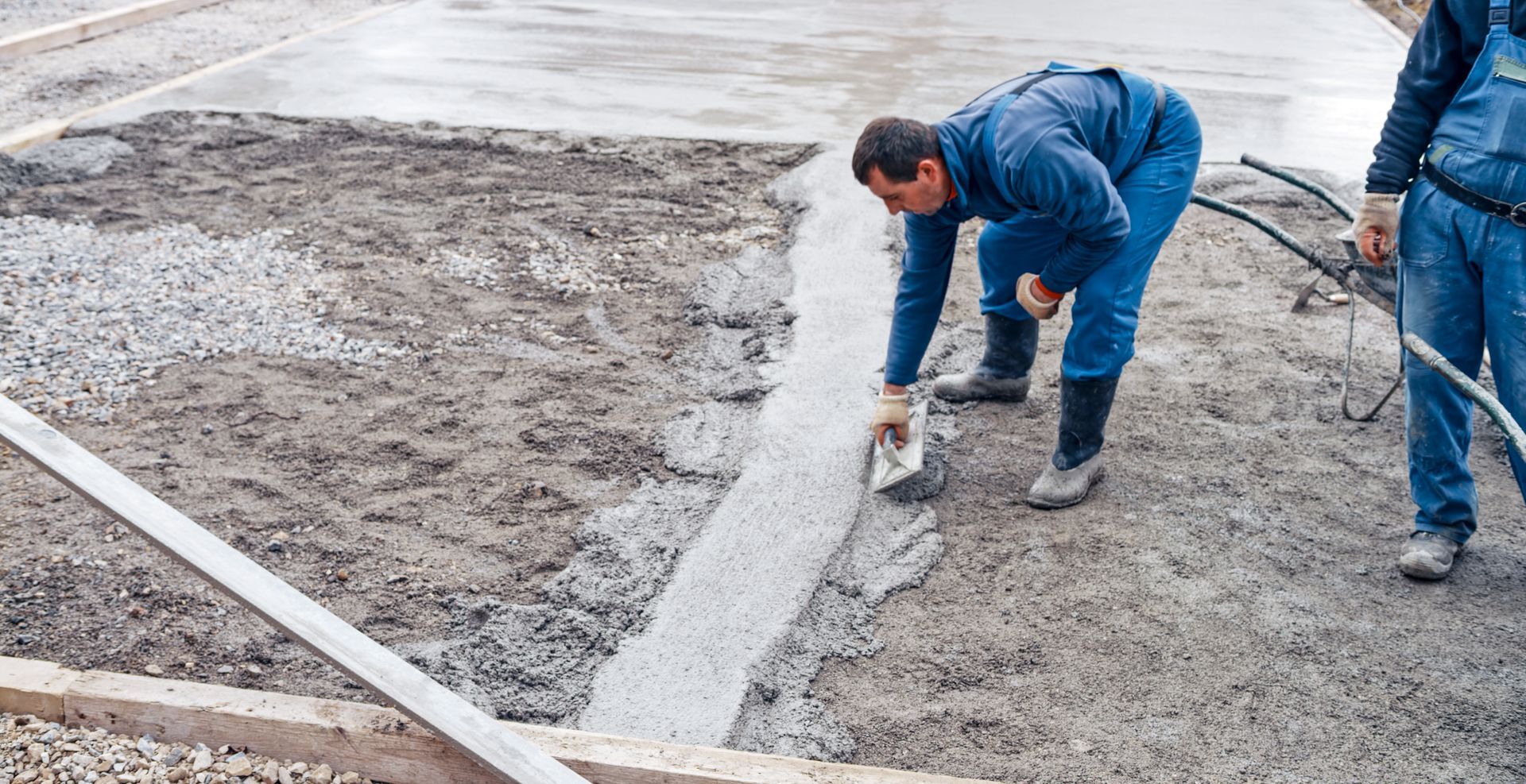 Two men applying concrete, showcasing skilled labor by a residential concrete contactor on-site.