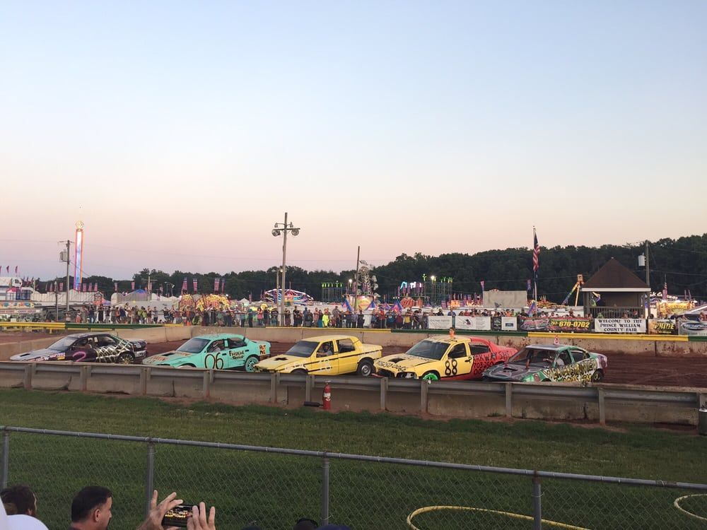 A group of cars are racing on a dirt track
