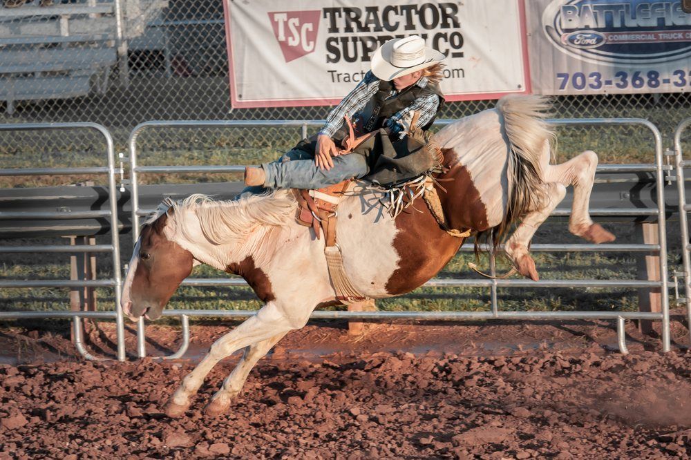 A man is riding a brown and white horse in a rodeo arena