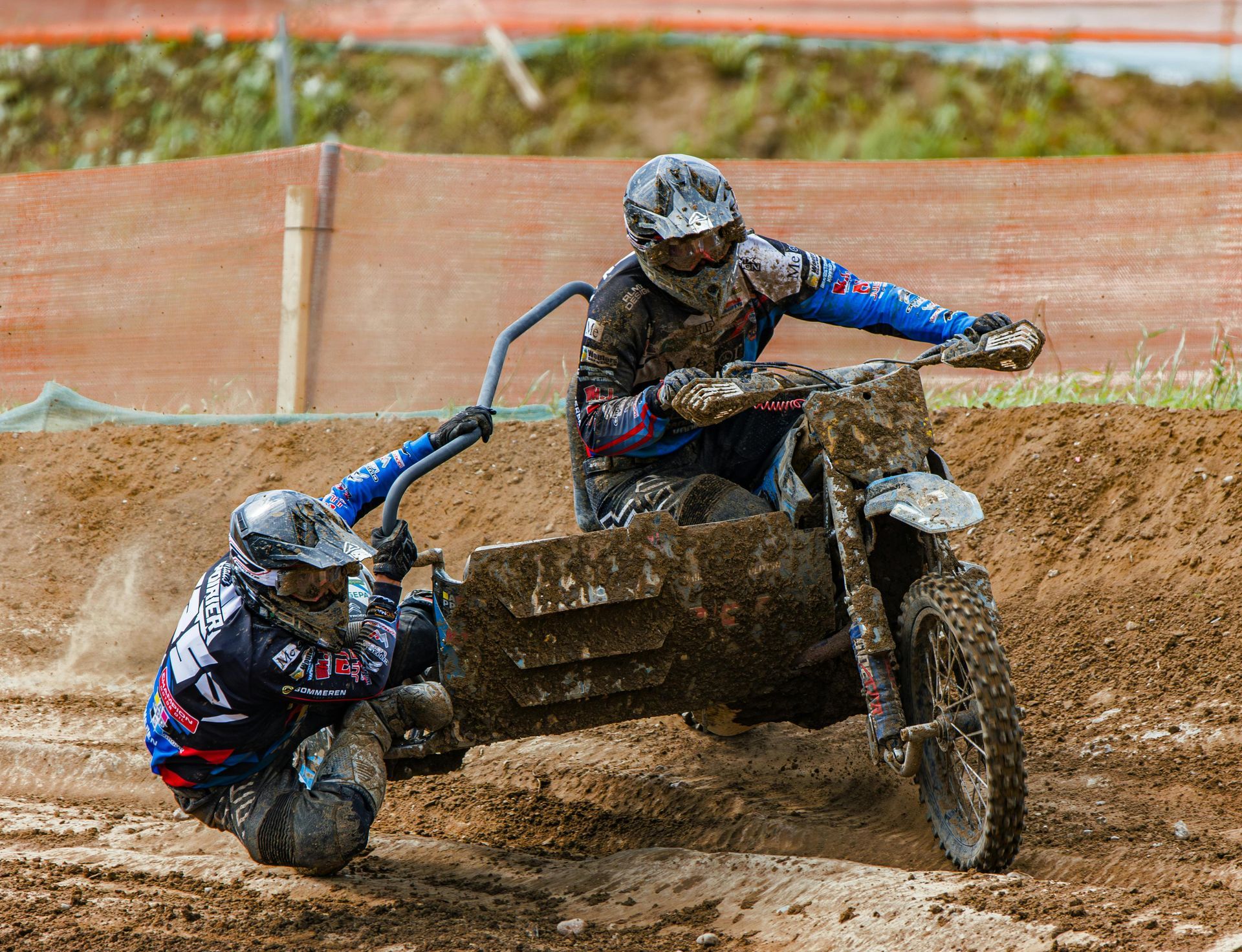 Two men are riding sidecar motorcycles on a dirt track.