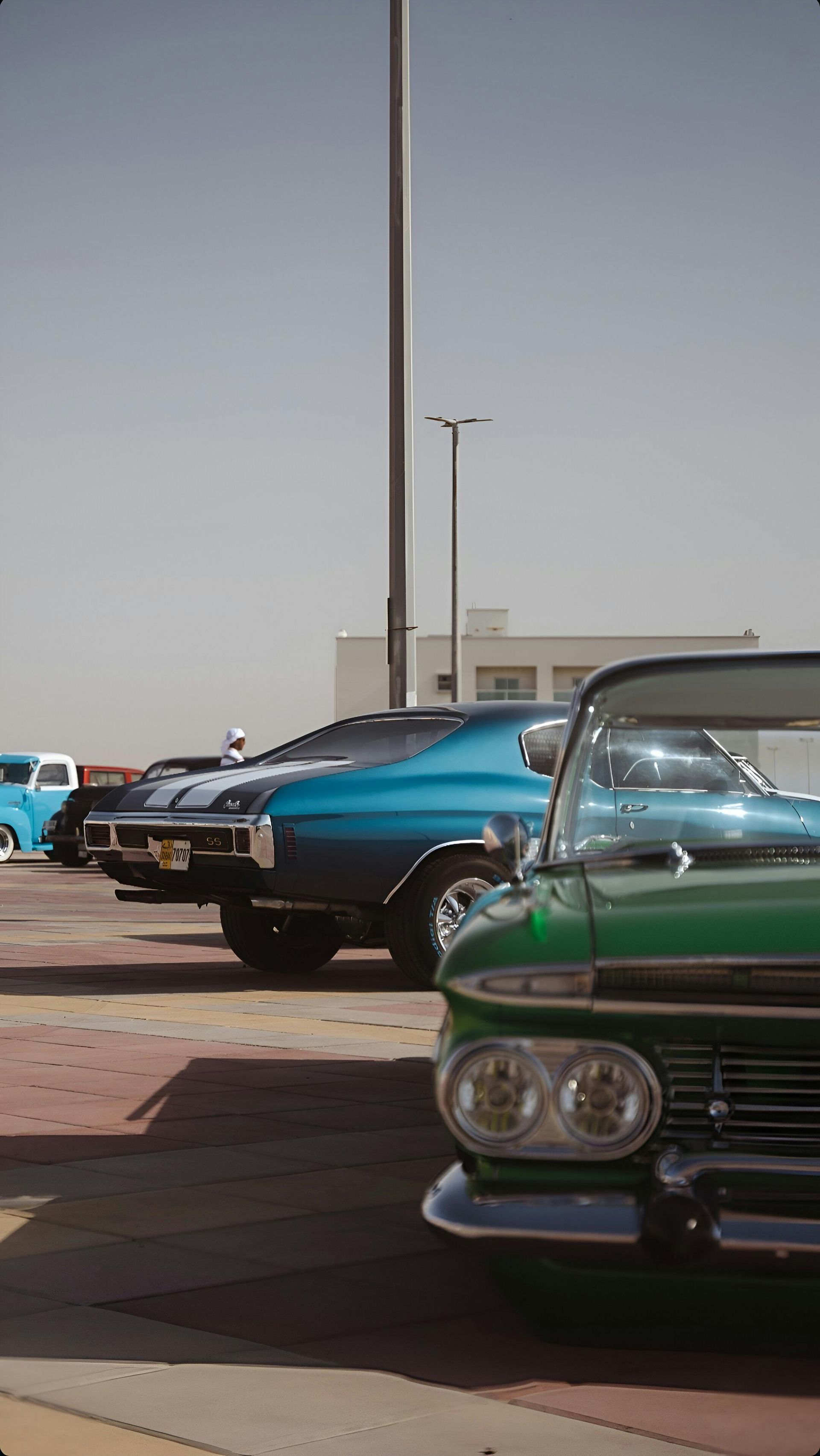 A green car is parked next to a blue car in a parking lot.