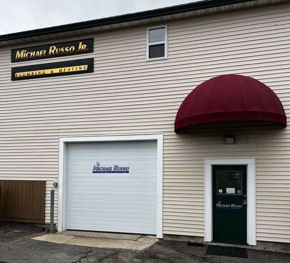 Exterior of Michael Russo Jr. business with garage door, awning, and door. Building is beige.