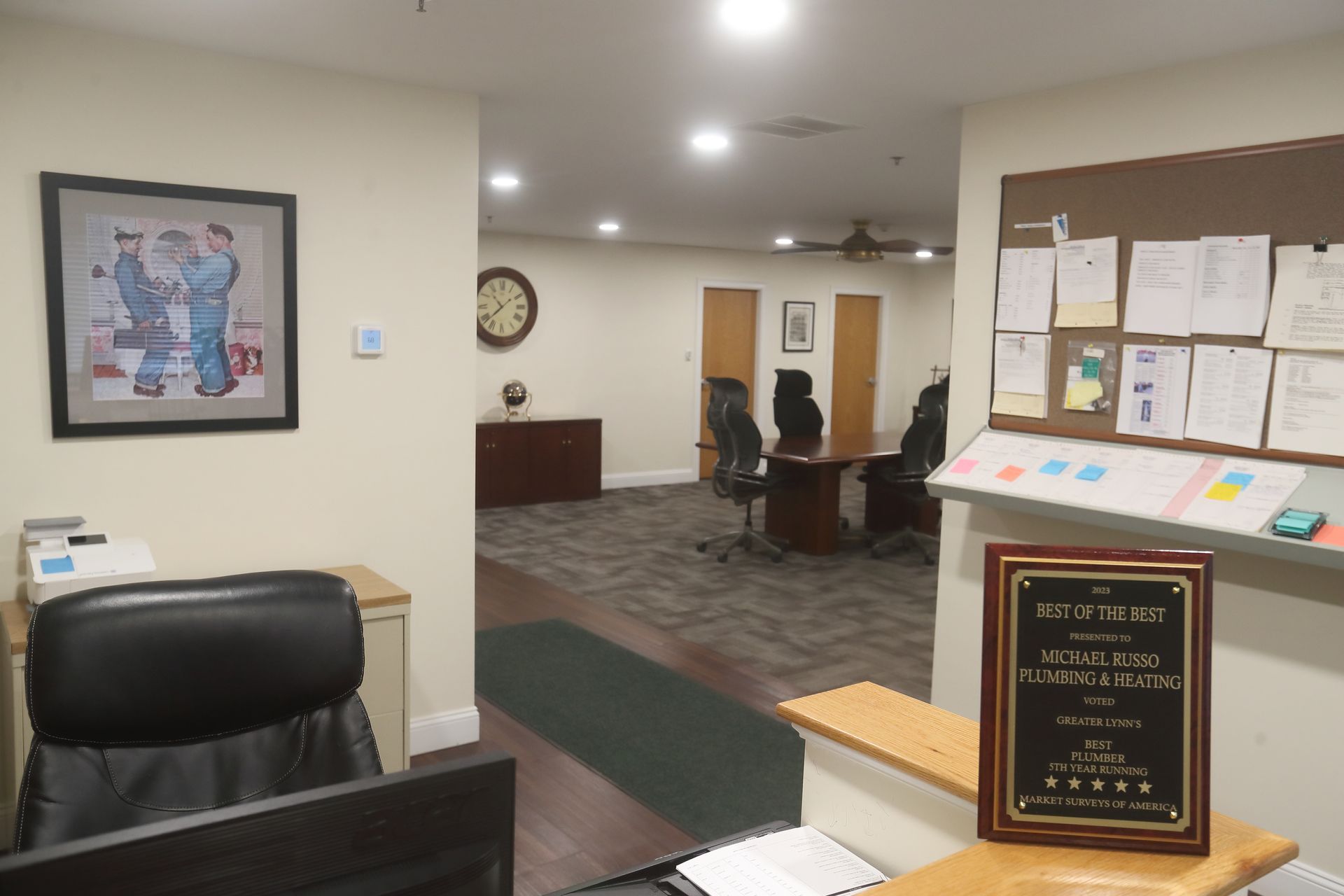 Long hallway with black rugs, art, and a red pipe on the ceiling.