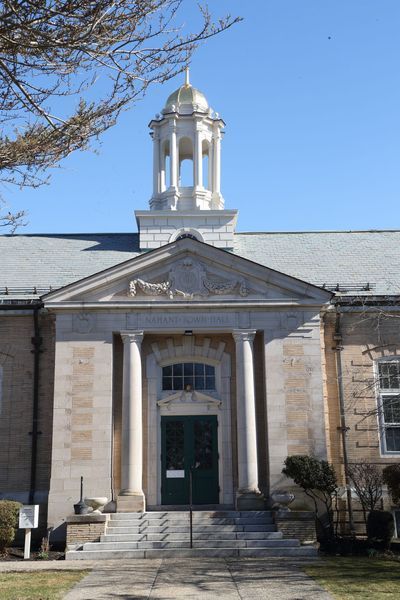 Stone building with columns, green door, and gold-topped cupola, under a clear blue sky.