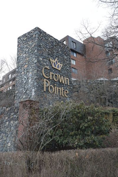 Stone sign for Crown Pointe apartment building. Gold lettering with crown logo.