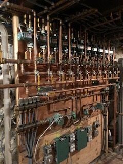 Copper pipes and valves on wooden paneling, likely a mechanical or utility room.