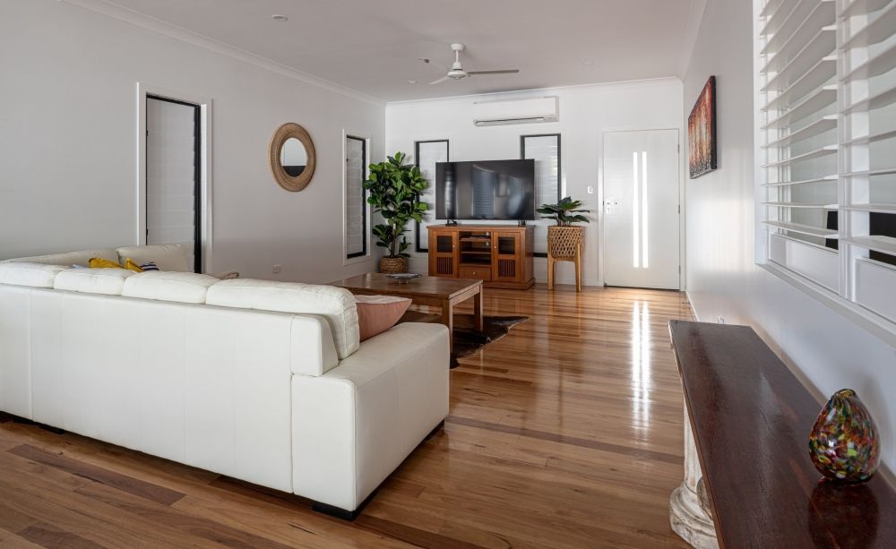 A Living Room With a White Couch, Wooden Floors, and a Flat Screen Tv — Wilkinson Homes in Annandale, QLD
