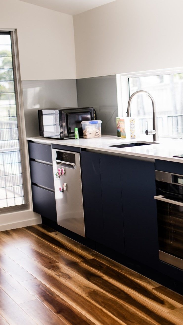 A Kitchen With Blue Cabinets, Stainless Steel Appliances, a Sink, and a Window — Wilkinson Homes in Annandale, QLD