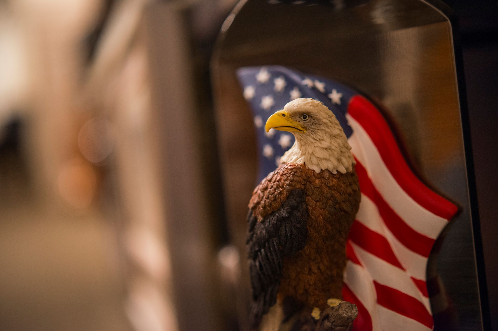 A bald eagle is sitting on top of an american flag.