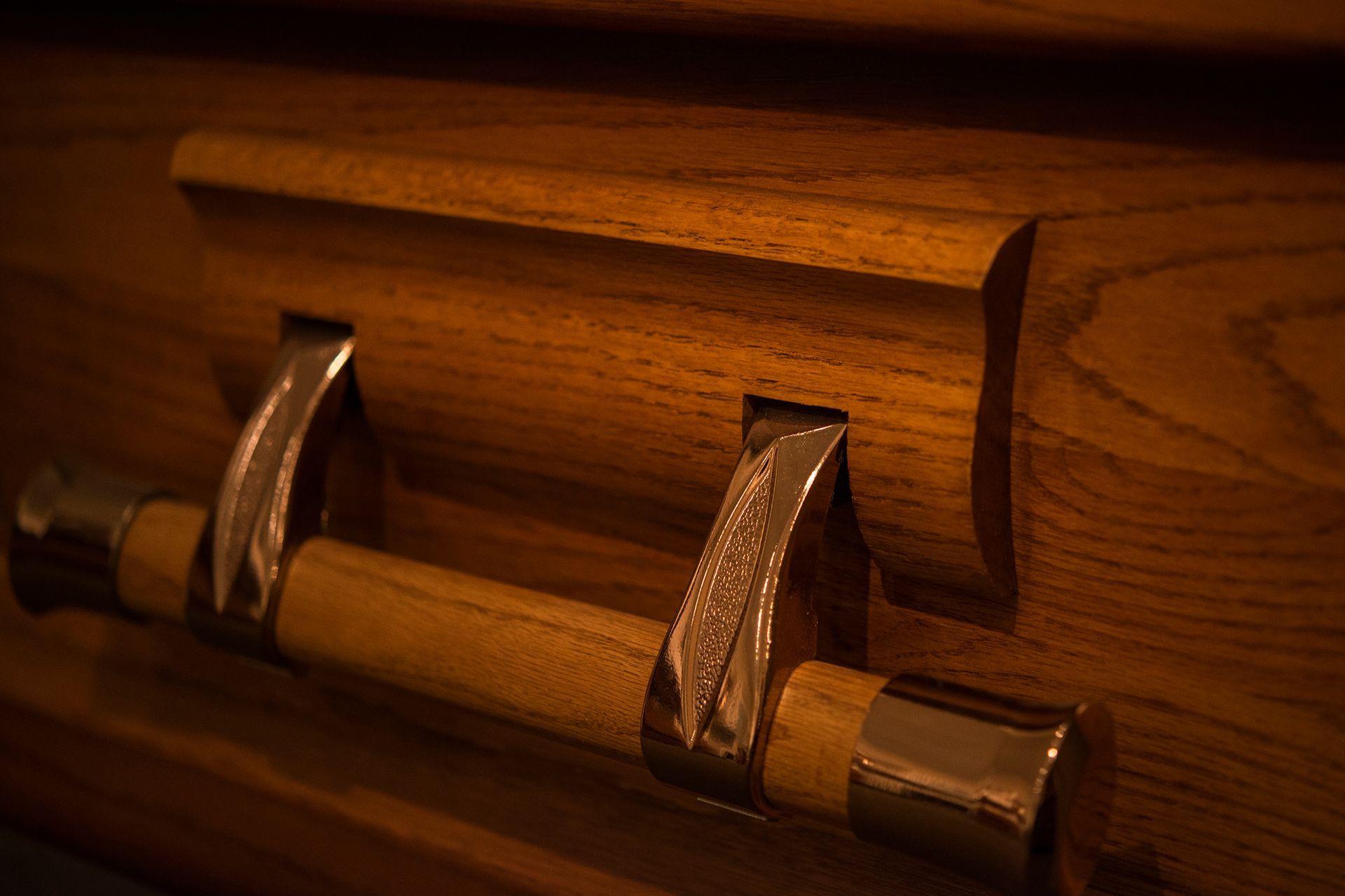 A close up of a wooden coffin with metal handles.