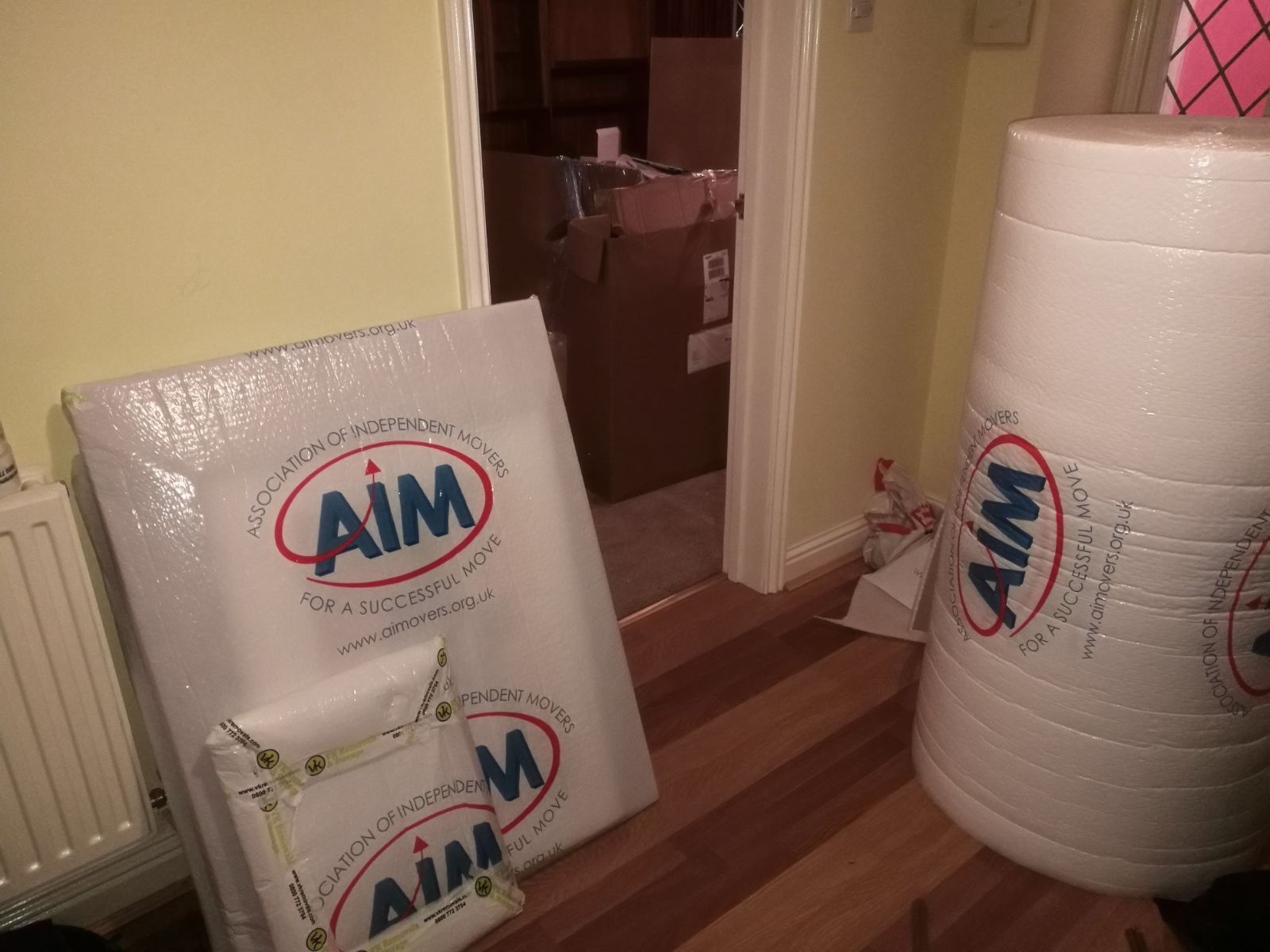 Bubble wrap packaging with AIM logo in a room with an open doorway and wooden floors.