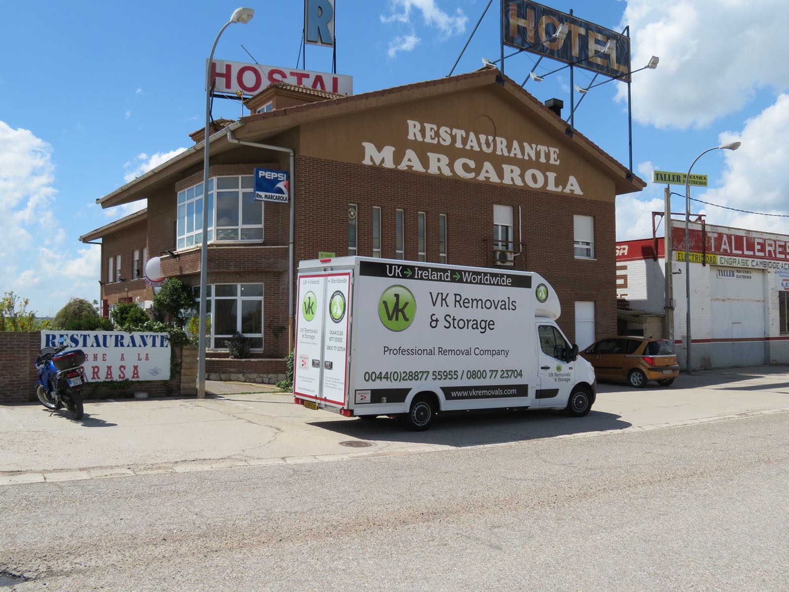 A white moving van parked outside a brown building with a