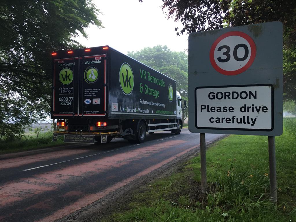 Truck on road, passing a 30 mph speed limit sign with