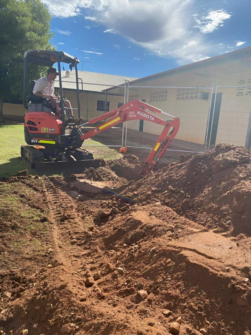 A Man With A White Shirt Driving Small Kubota Excavator — NQES Industries in Ryan, QLD