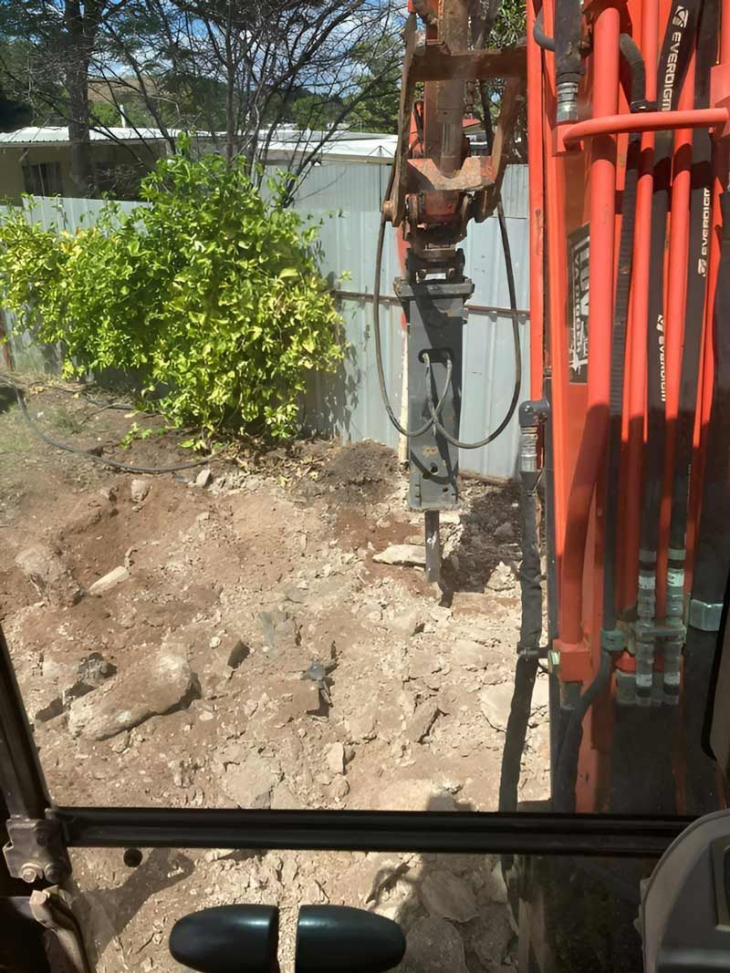 A Person Is Driving An Excavator Demolish The Concrete Slab In The Backyard — NQES Industries in Cloncurry, QLD