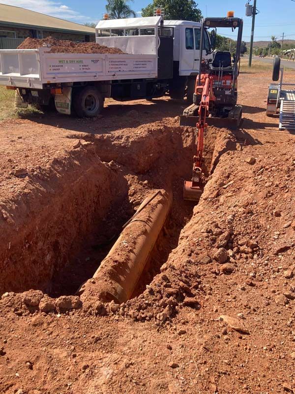 A Mini Digger Is Excavating For The Water Pipe — NQES Industries in Cloncurry, QLD