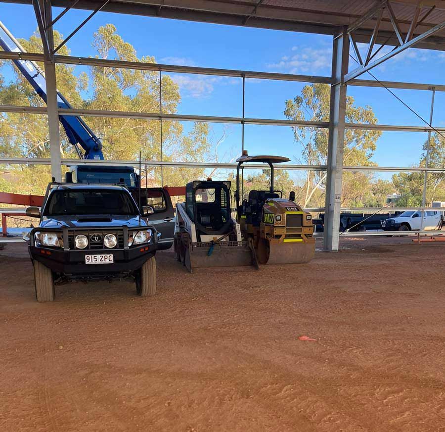 A Truck Rests Beside A Bulldozer Near The Large Metal Storage Shed — NQES Industries in Cloncurry, QLD
