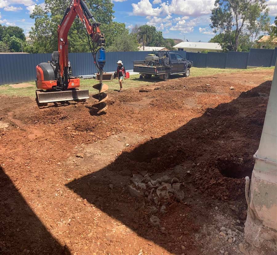A Digger Operates On A Dirt Pile In A Yard — NQES Industries in Cloncurry, QLD