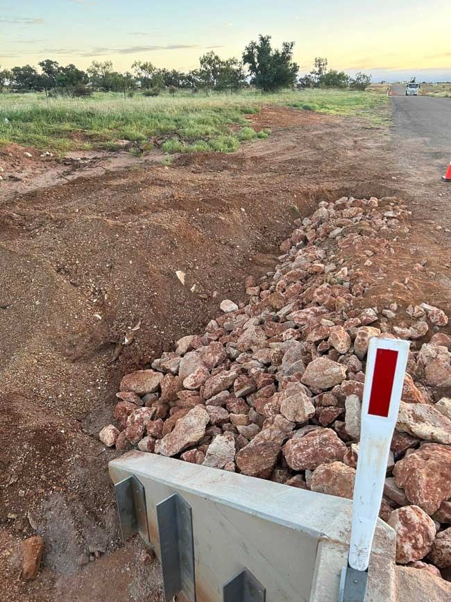 A Pile Of Rocks Is Sitting On The Side Of A Dirt Road — NQES Industries in  Mount Isa, QLD