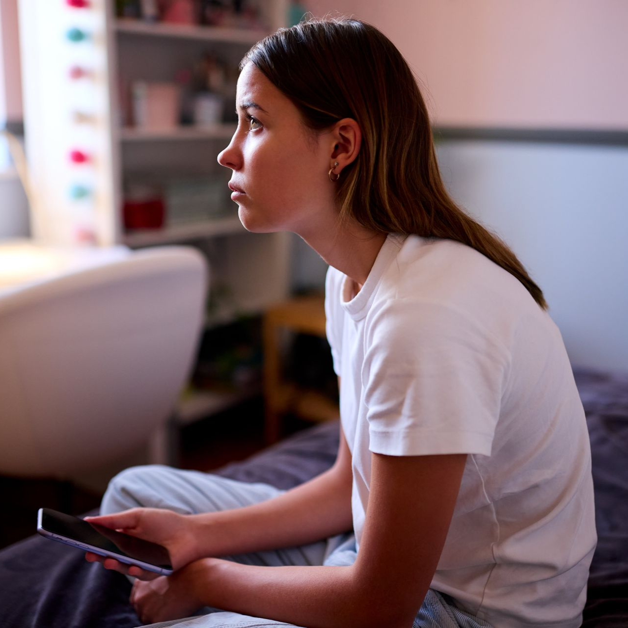 A woman is sitting on a bed with her head down