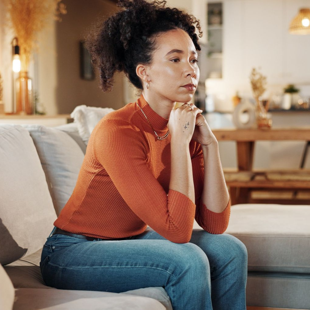 A woman is sitting on a bed with her head down