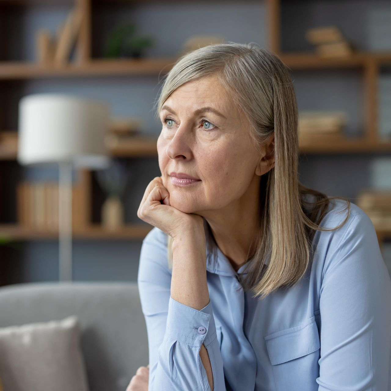 A woman is sitting on a bed with her head down