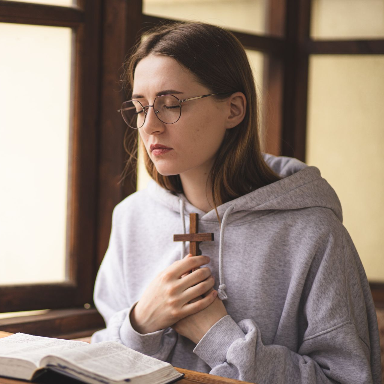 A woman is sitting on a bed with her head down
