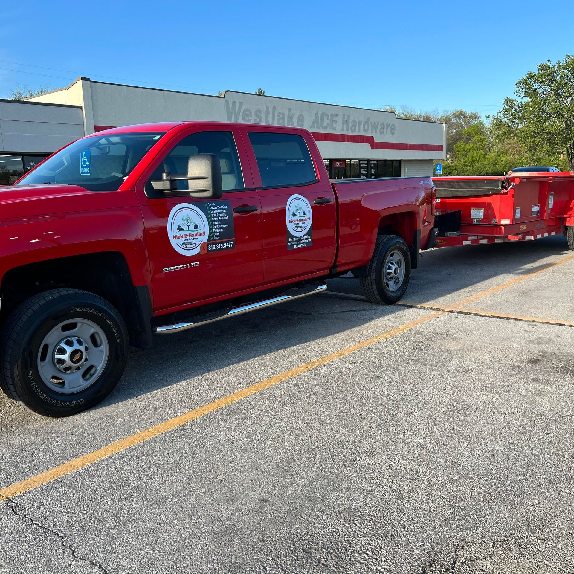 Red truck pulling a red trailer in front of a Westlake Ace Hardware store.