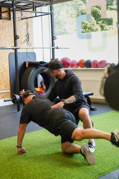 Een man doet push-ups met een trainer in de sportschool.