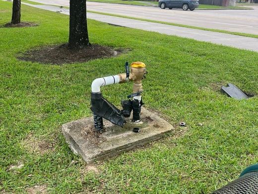 Gas meter with white pipe on concrete pad in a grassy yard near a street