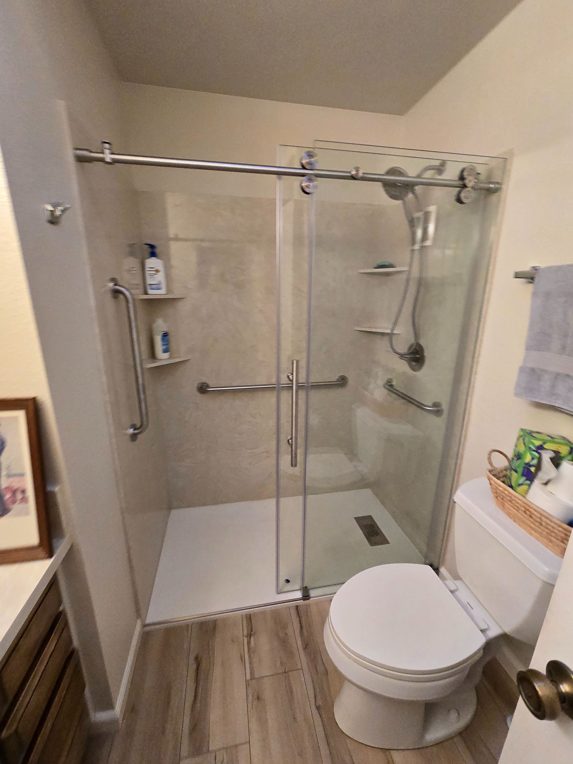Accessible bathroom with sliding glass shower door, grab bars, and toilet.