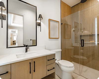 Modern bathroom with light wood vanity, black fixtures, and glass shower.