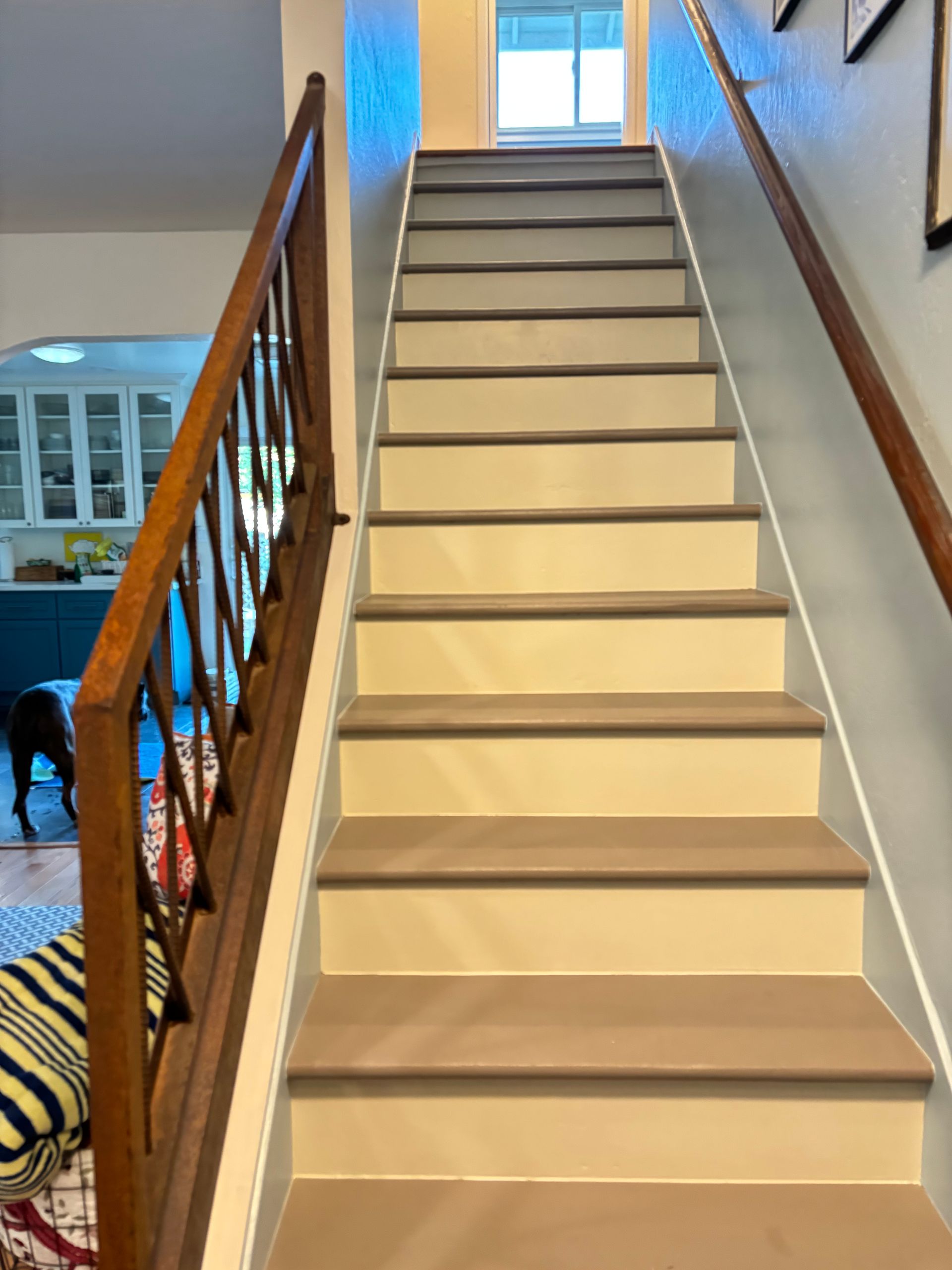 Staircase with light brown treads, dark trim, and wooden handrails, leading upwards.