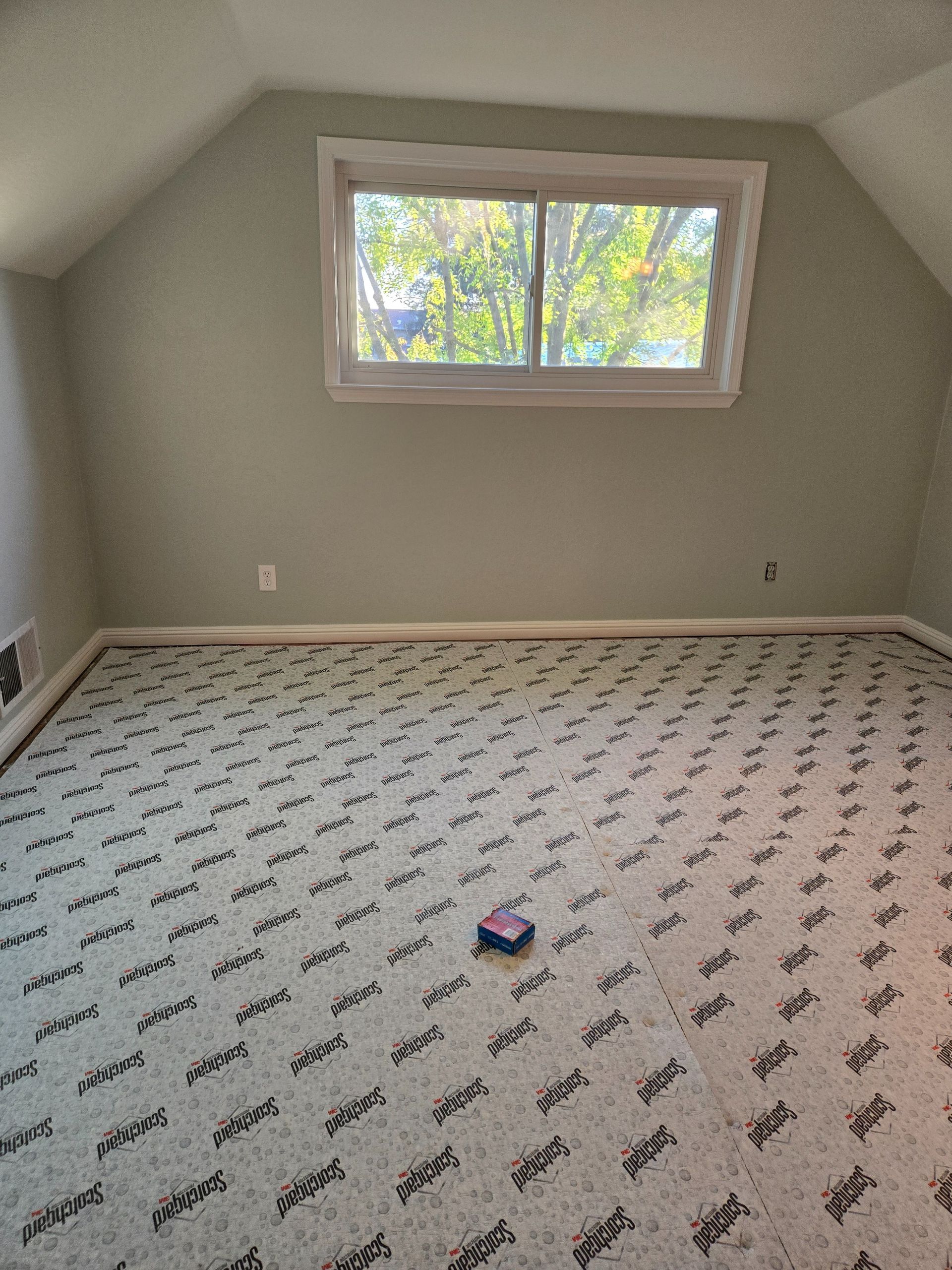 Empty room with green walls and patterned flooring, a window, and a light switch.