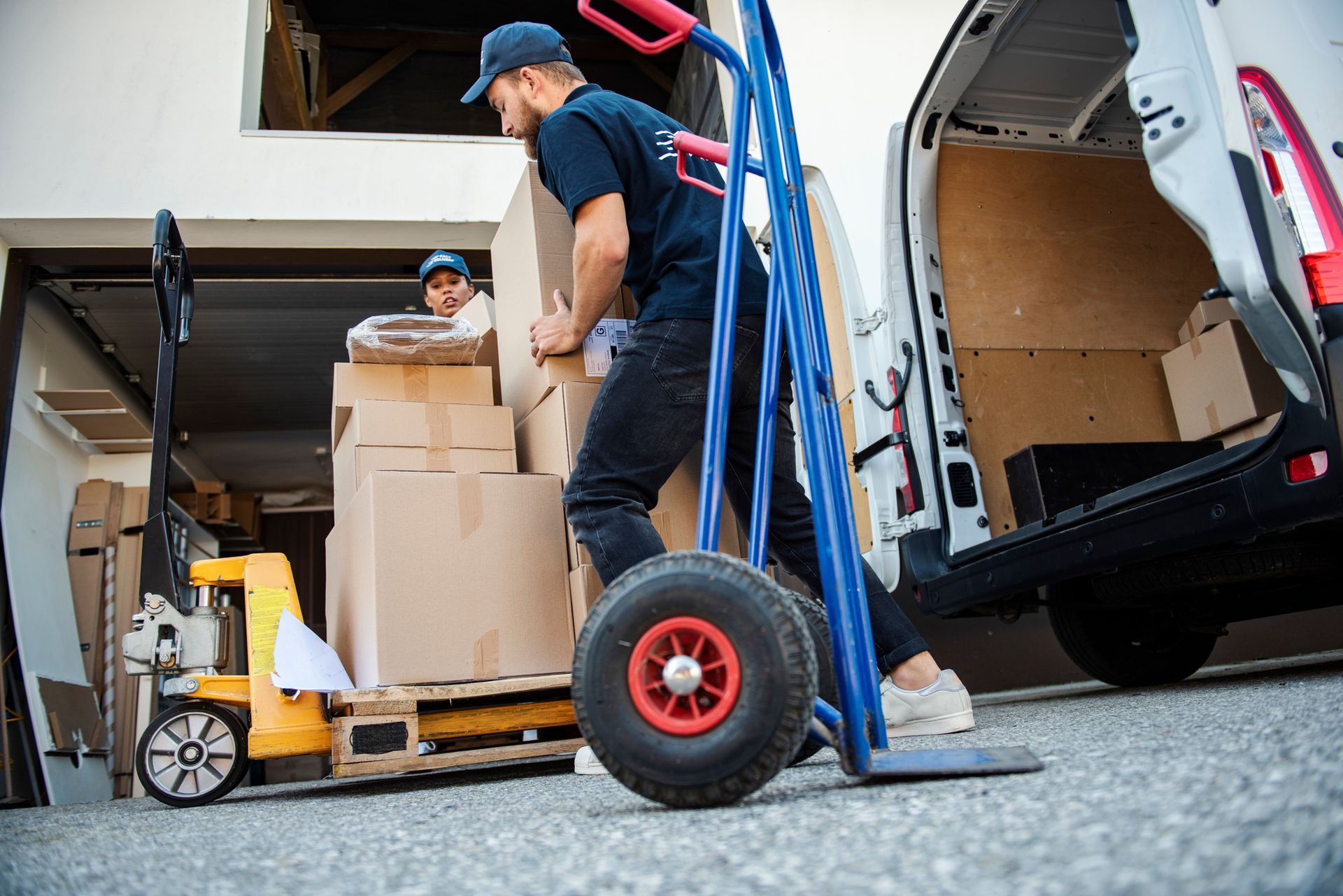 A man is pushing a hand truck full of boxes into a van.