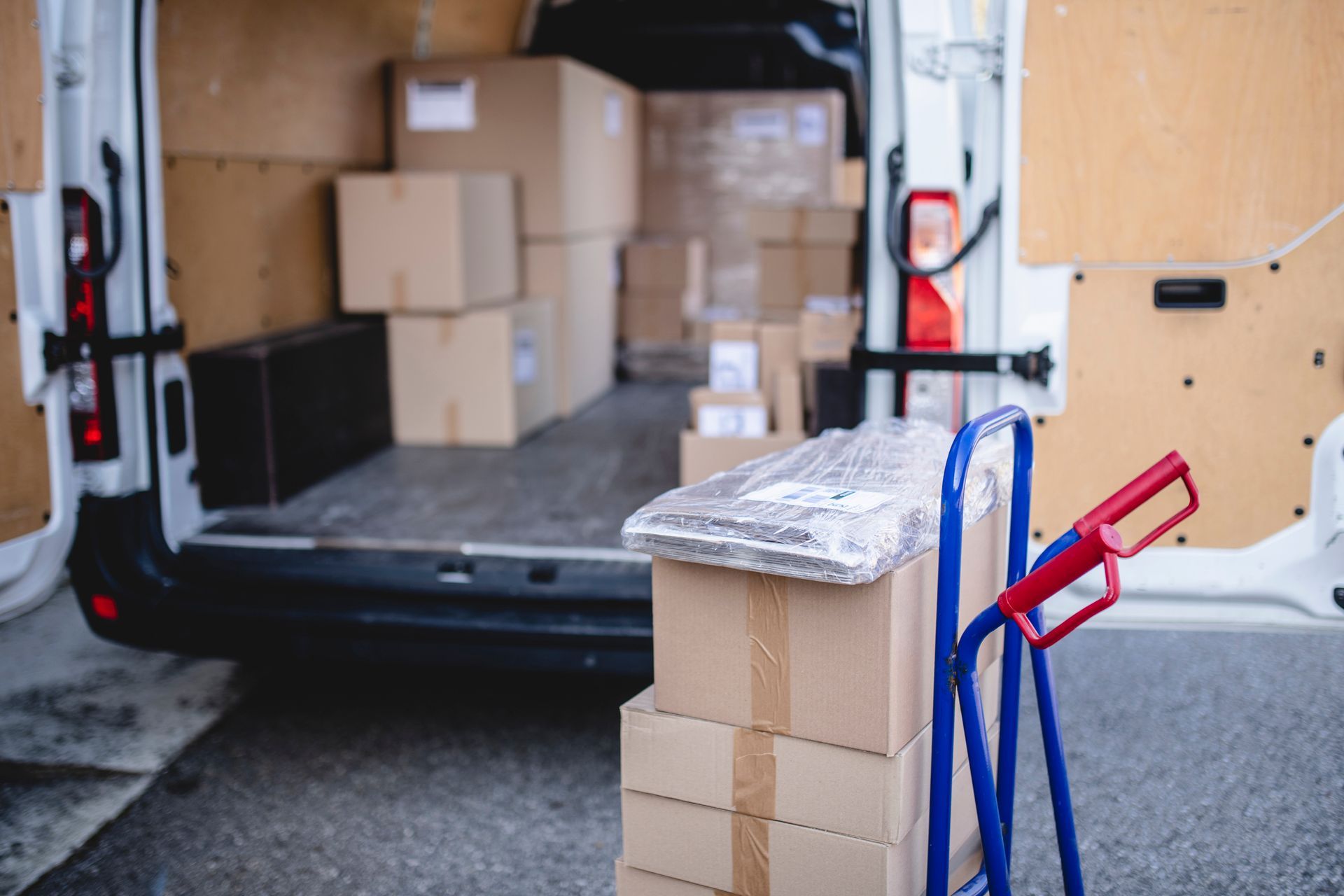 A delivery van filled with boxes and a hand truck.