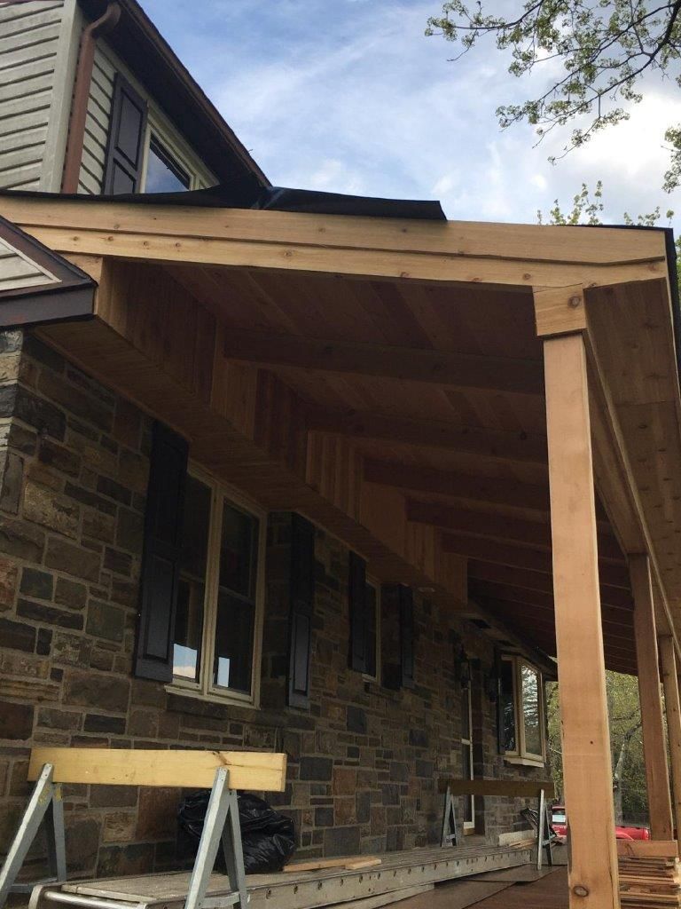 A wooden porch is being built on the side of a brick house.