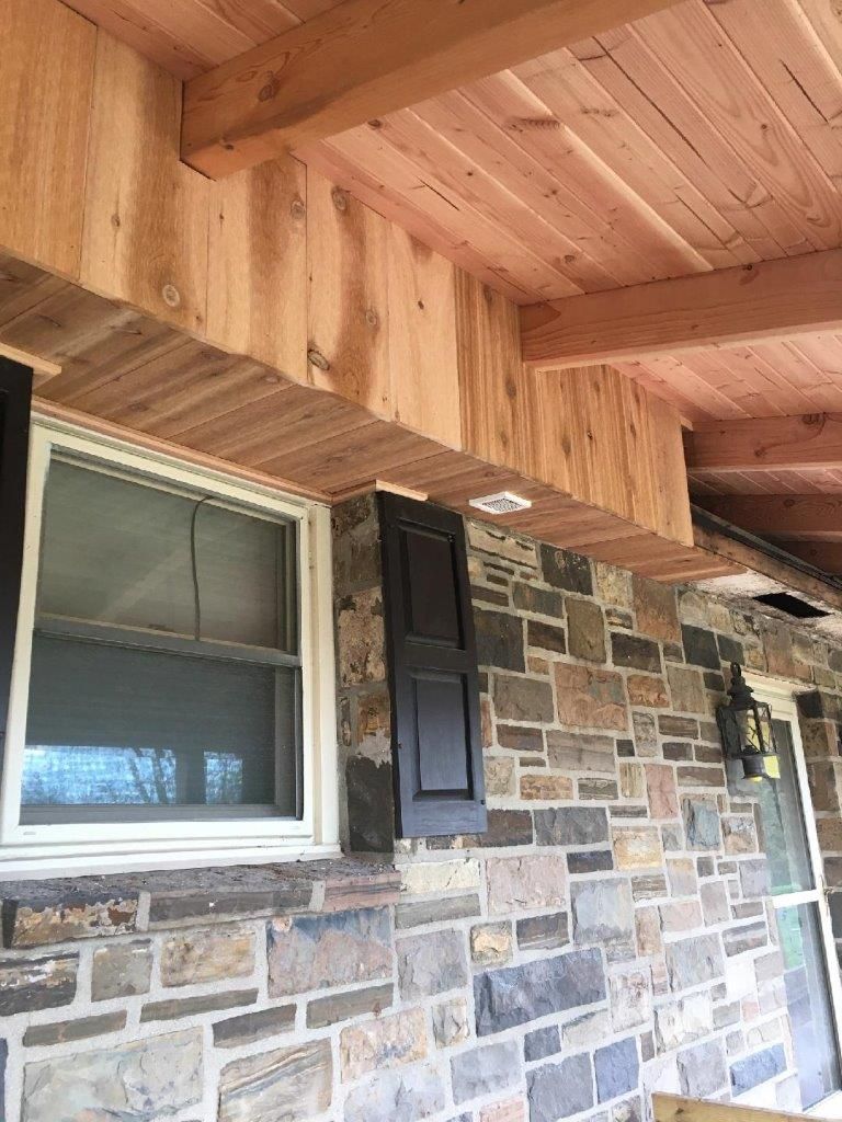 A stone wall with a wooden ceiling and a window.