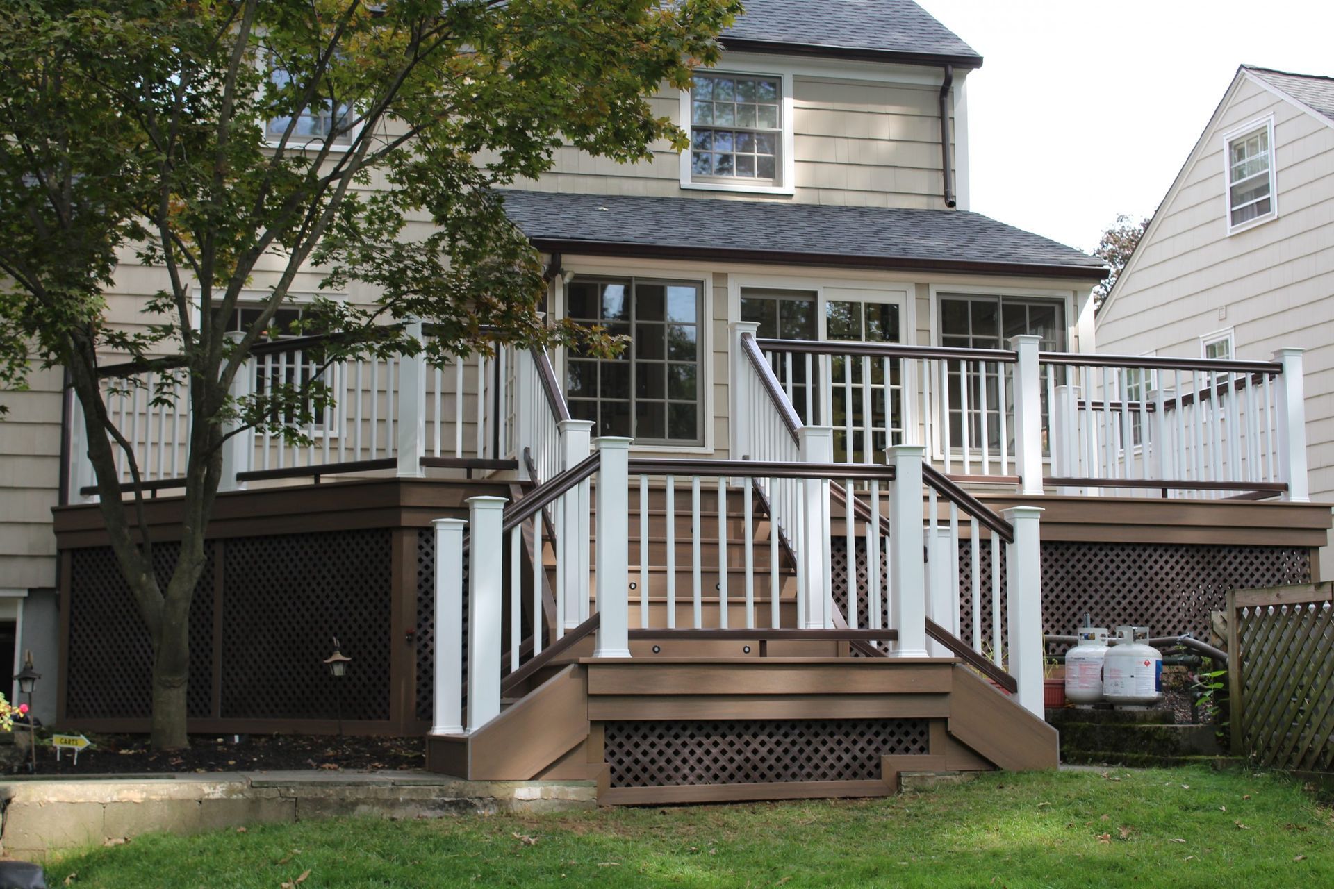 Multi-level deck with white posts and brown railings attached to residential home in NJ