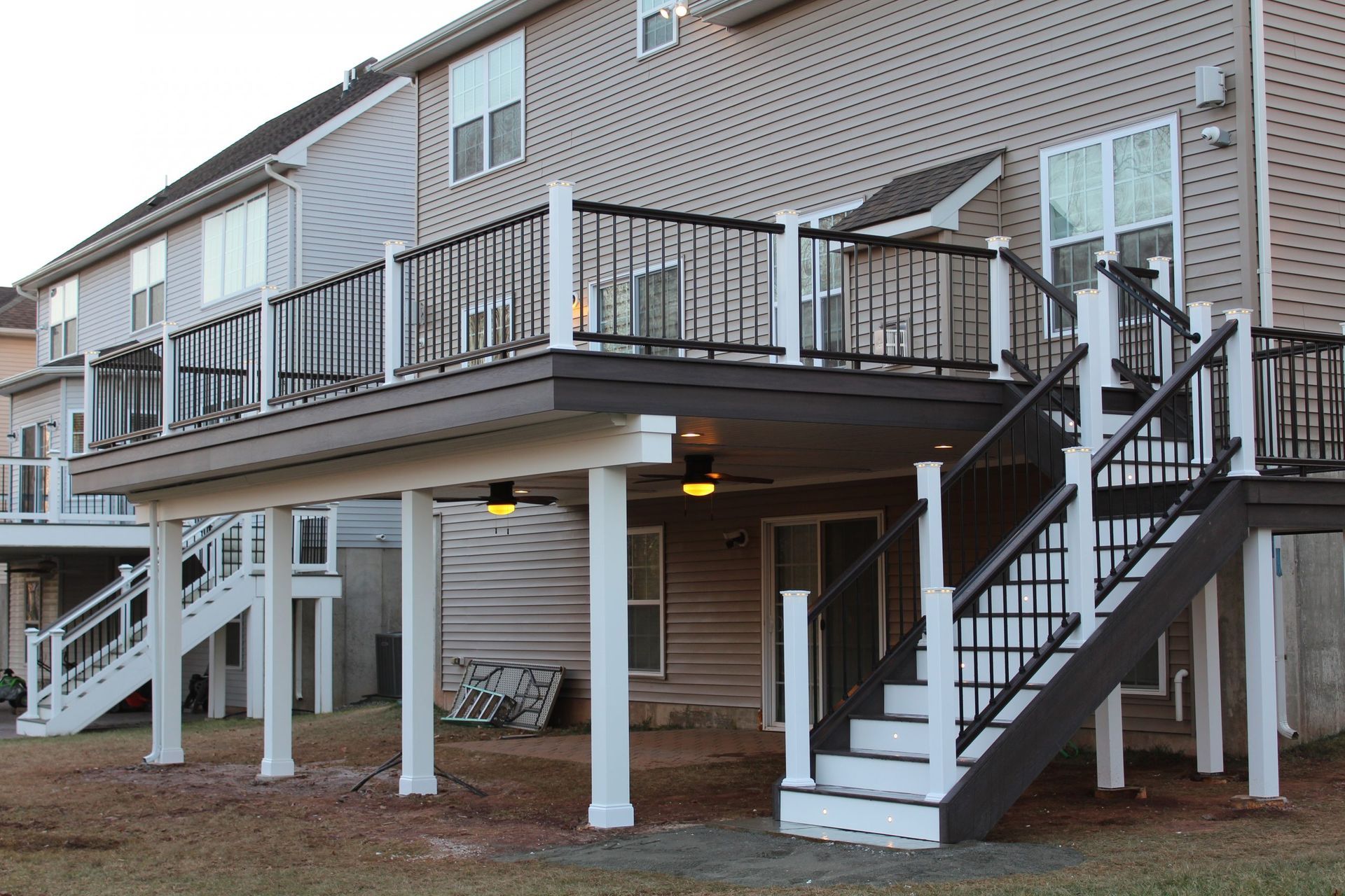 Second-story deck with black and white railings featuring under-deck lighting by New Dimensions
