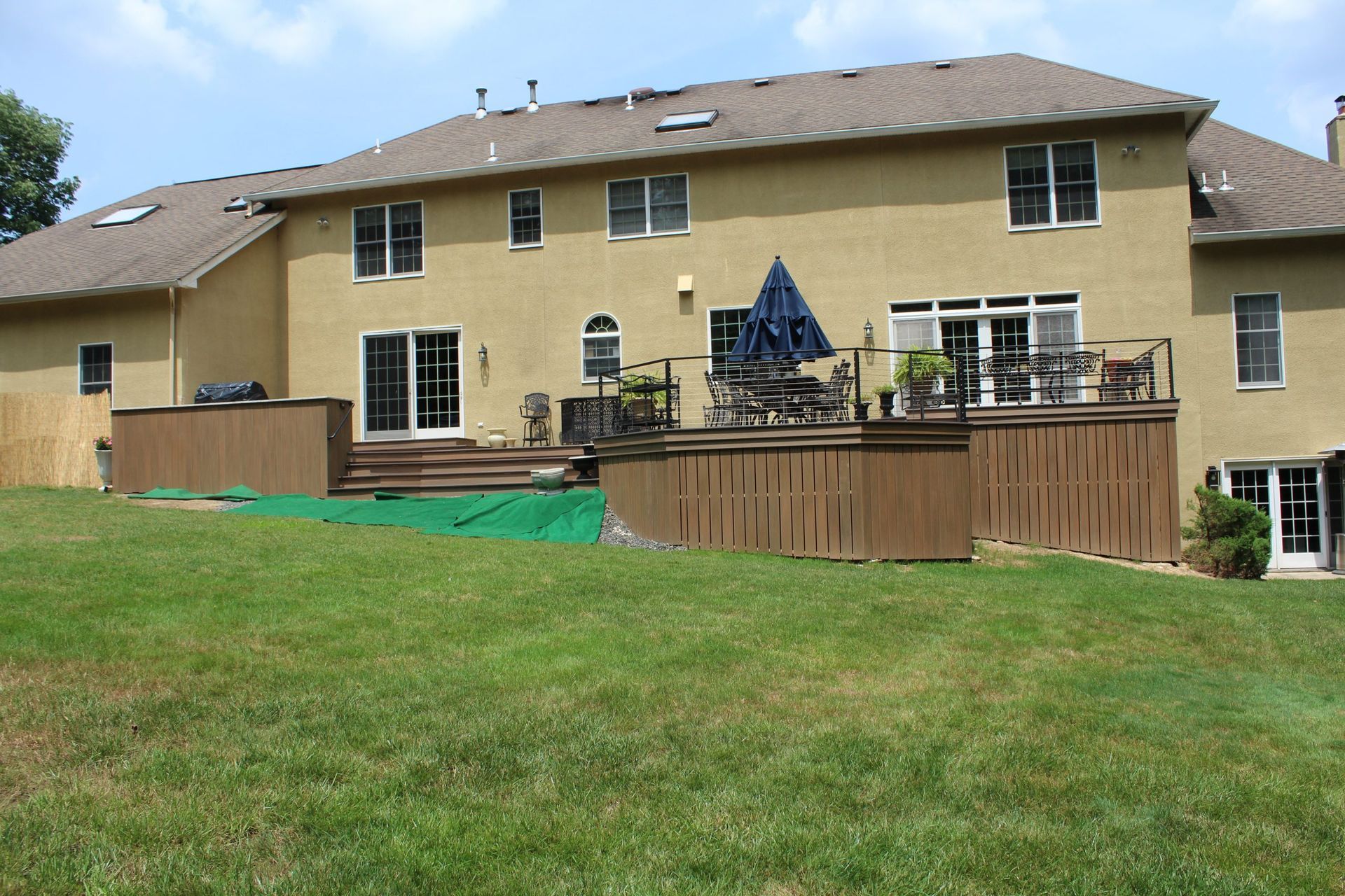 Elegant elevated deck with lighting, white posts, and black railings by New Dimensions NJ