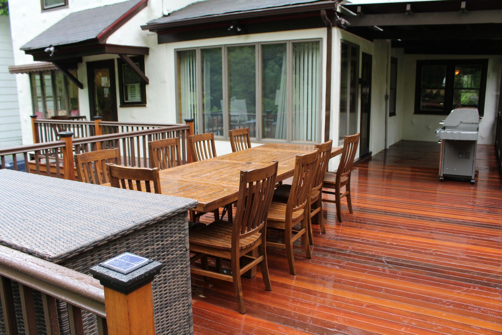 Wooden deck with outdoor dining set and grill.