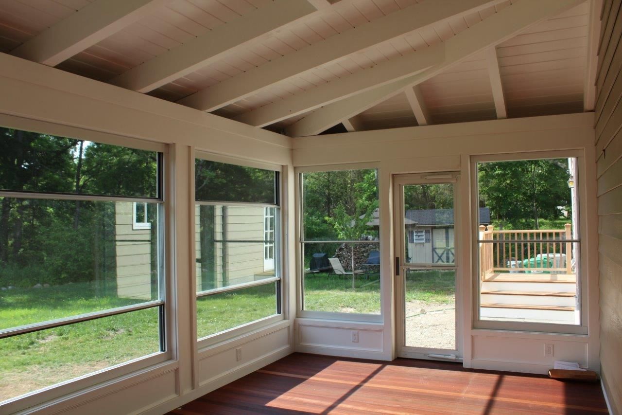 A screened in porch with lots of windows and a sliding glass door