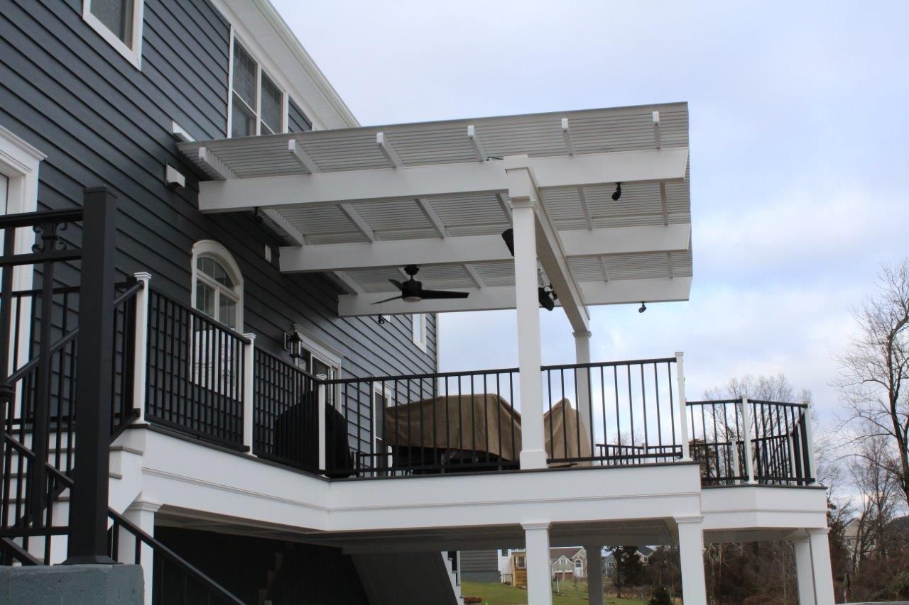 A large deck with a pergola and a ceiling fan