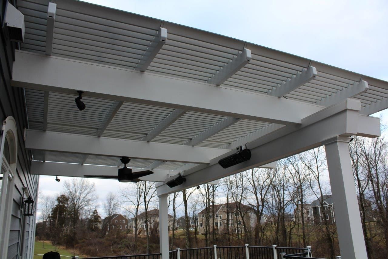A white pergola with a ceiling fan and heaters