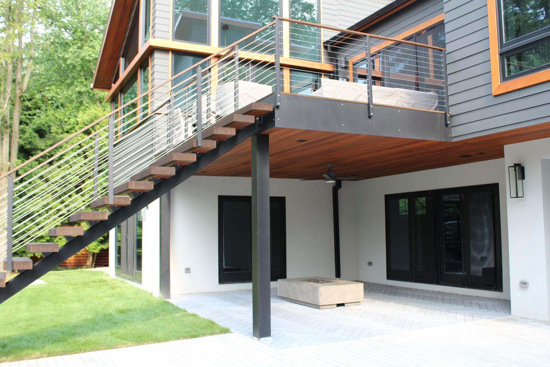 Modern deck with metal railings and wooden stairs.