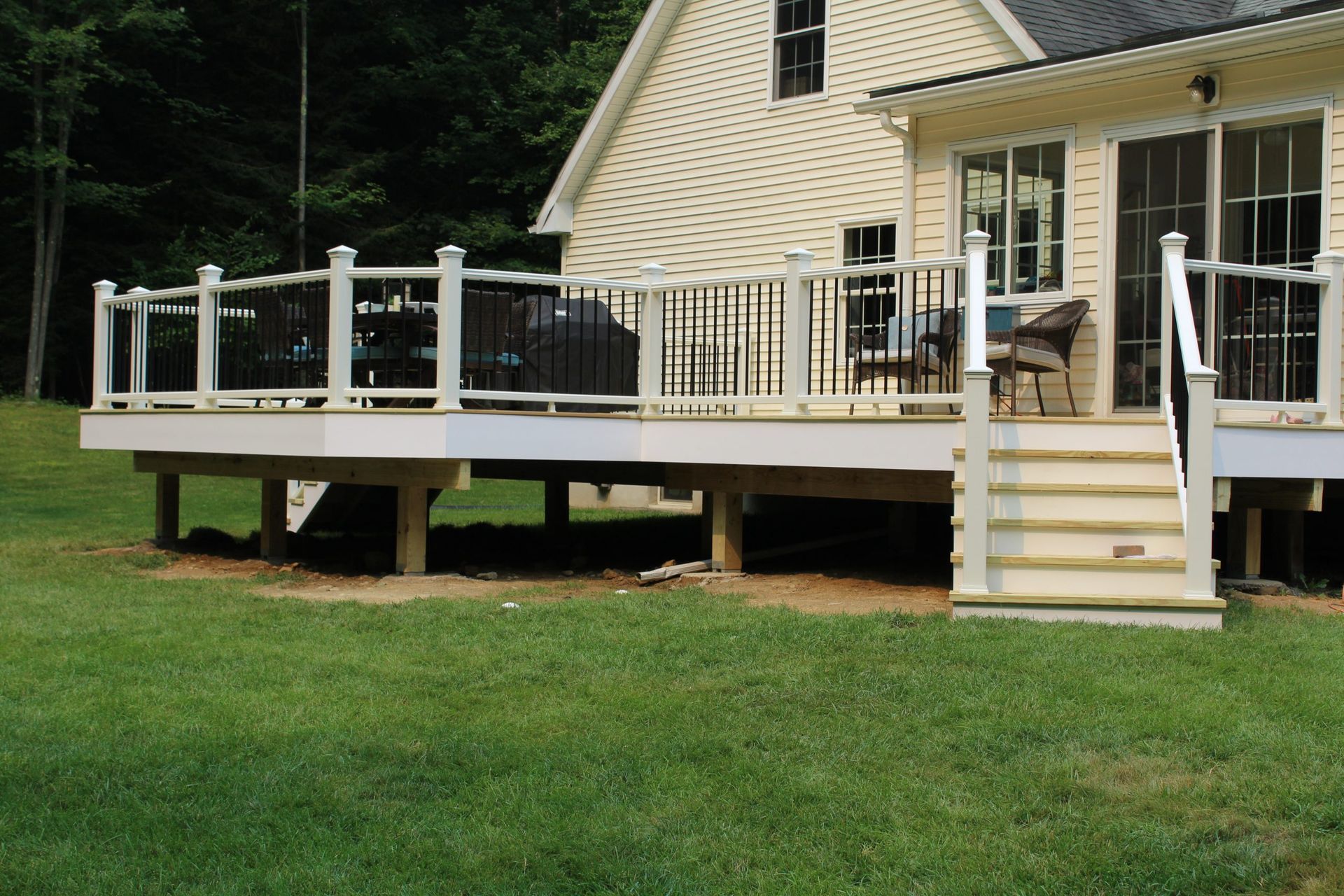 Elevated composite deck with white railings and stairs leading to backyard patio.