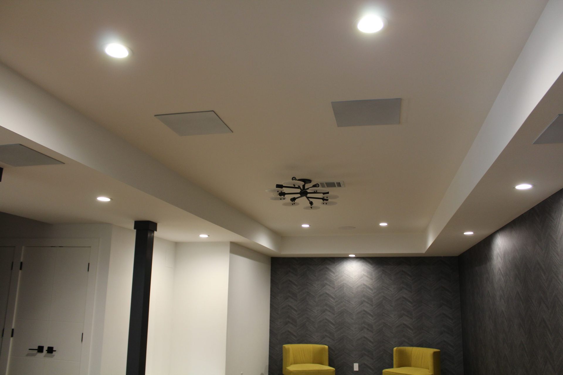 Ceiling view with recessed lighting and a contemporary chandelier in a modern basement.