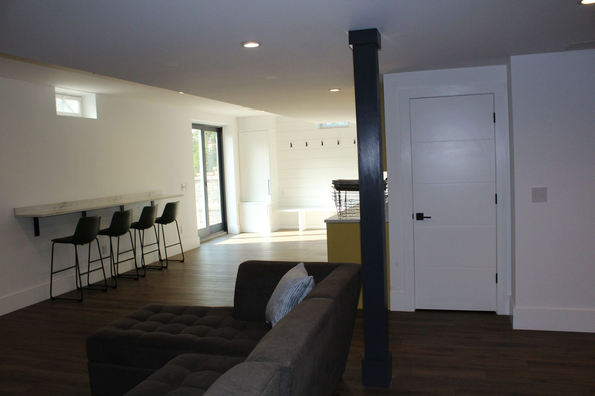 Spacious basement with sectional sofa, high bar seating, and modern minimal design.