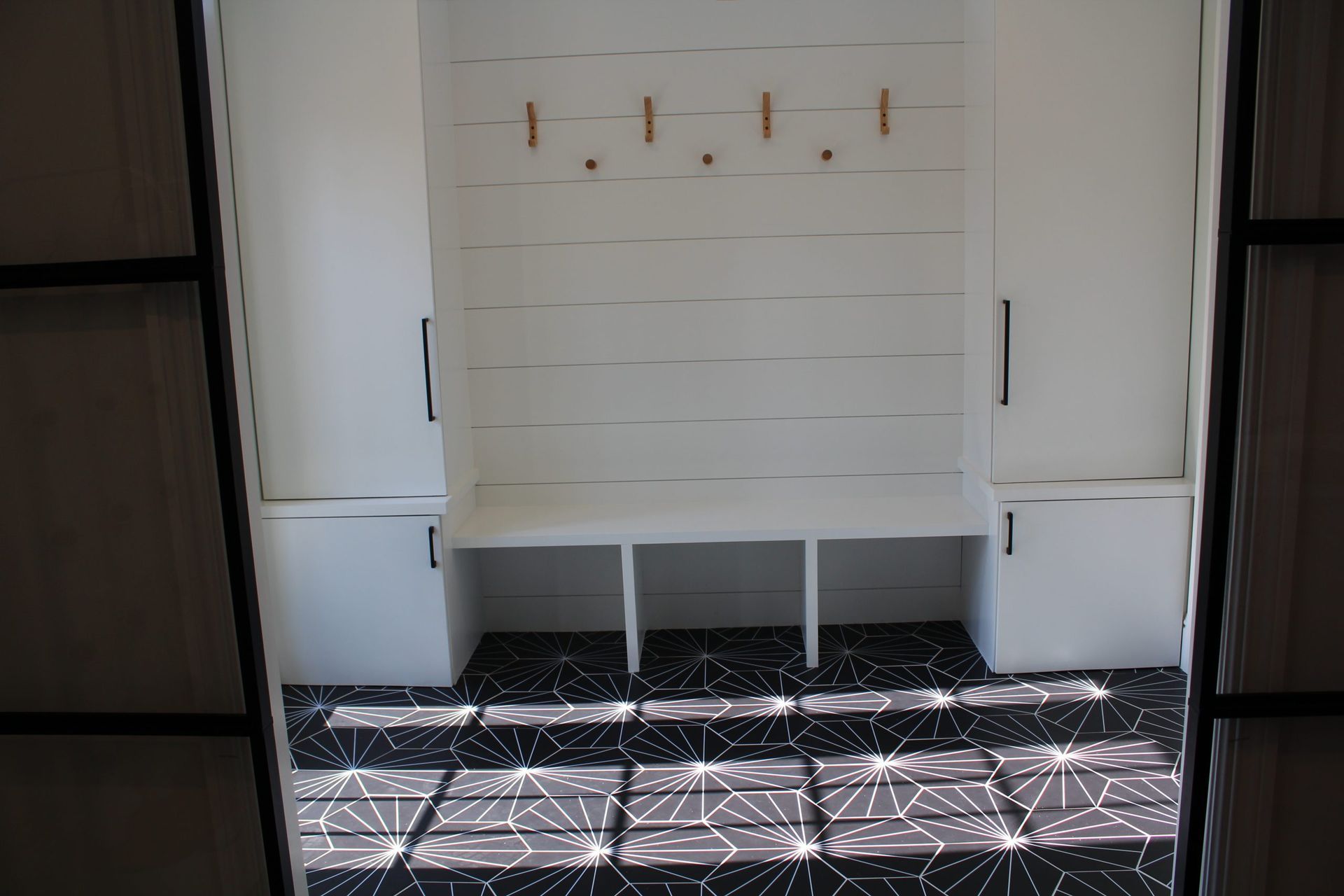 A white mudroom with bench seating and storage cabinets.